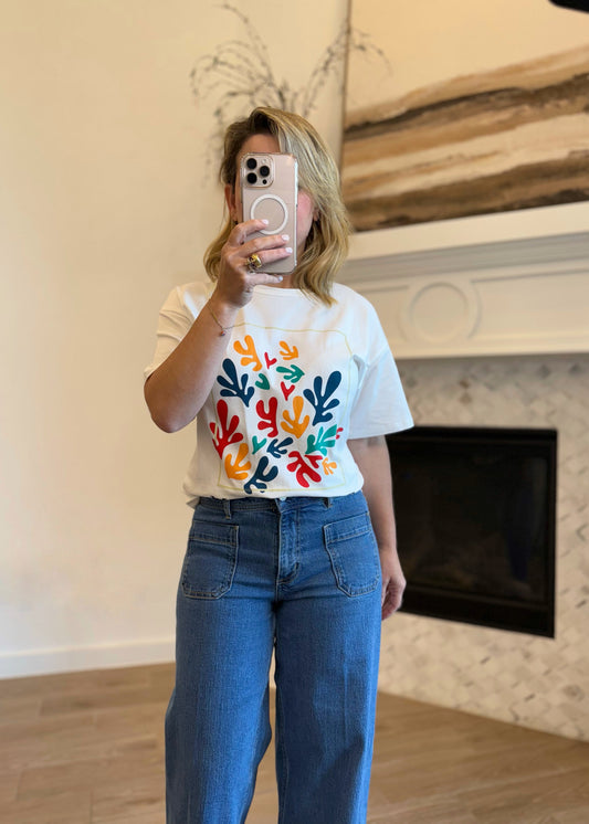 white t-shirt with colorful abstract design and blue jeans